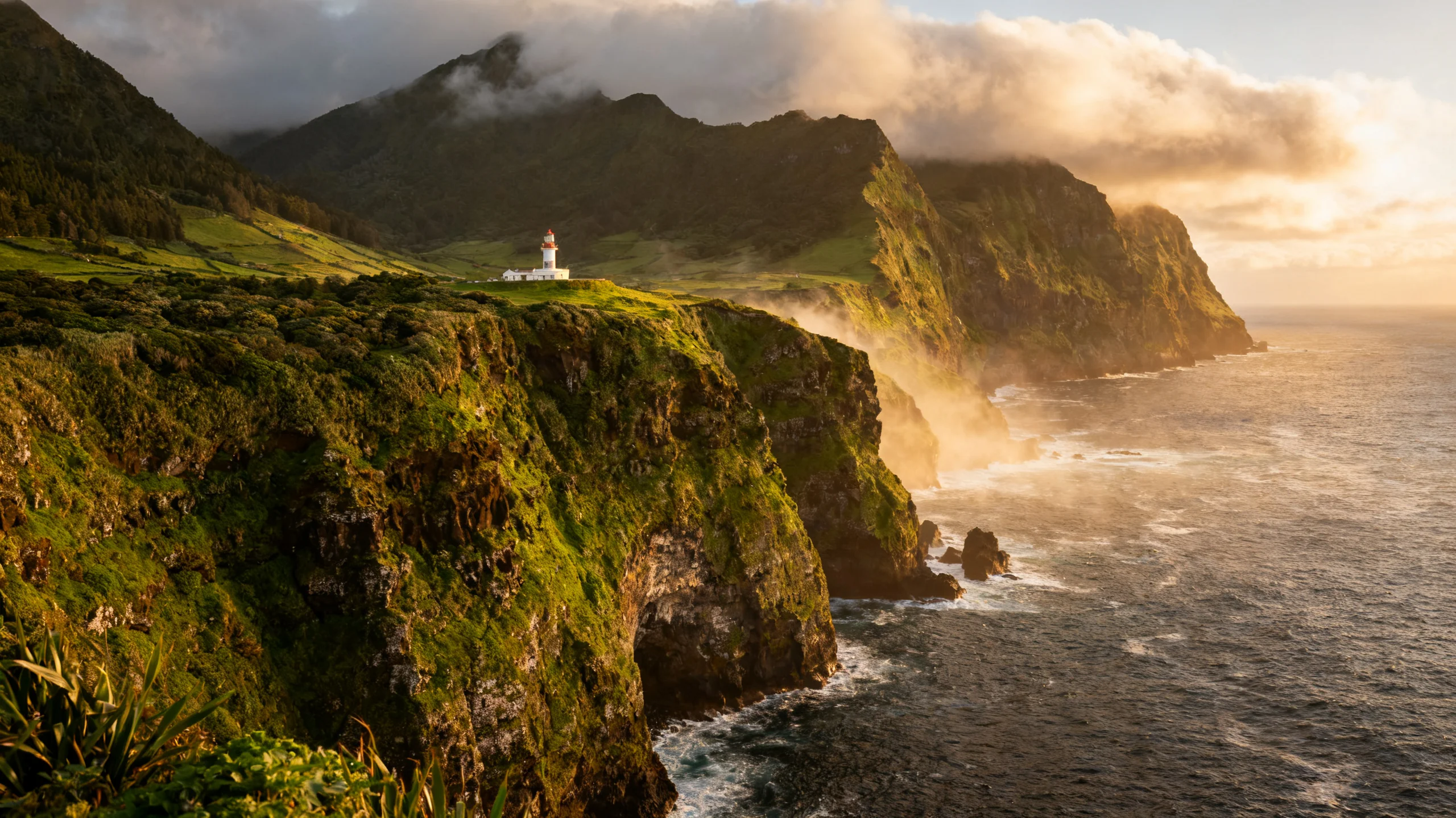 Rugged Nordeste coast with green cliffs and the Farol do Arnel lighthouse